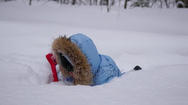 Un niño divertido juega con una pala de juguete en la nieve — Vídeo de stock