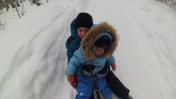 Счастливые дети катаются и улыбаются в снежной трубе по заснеженным дорогам — стоковое видео