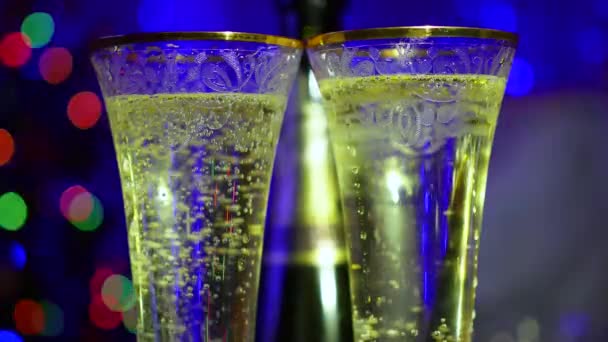 Bubbels mousserende wijn in glazen. In de achtergrond, bokeh lichten en slingers. — Stockvideo