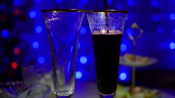 Rotwein wird in Gläser gegossen. im Hintergrund Bokeh-Lichter und Girlanden aus Weihnachtstannen — Stockvideo