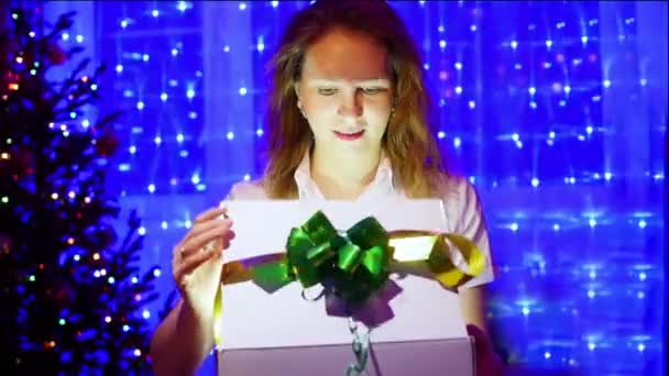 Surpresa de presente de Natal - Uma menina abre presente com estrelas mágicas. No fundo, bokeh luzes e guirlandas . — Vídeo de Stock