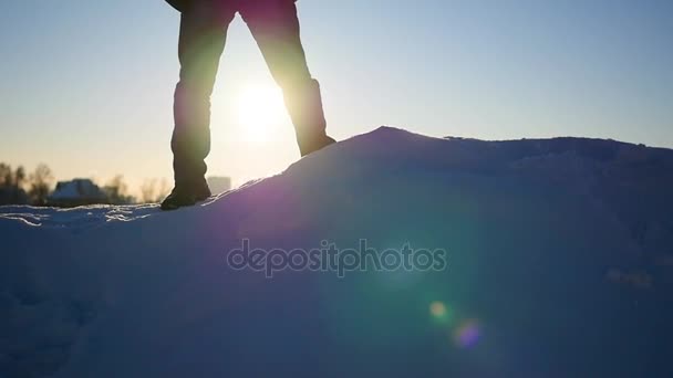 Der Kerl steht auf einem Schneehang und hebt bei Sonnenuntergang die Hände. Sport im Freien — Stockvideo