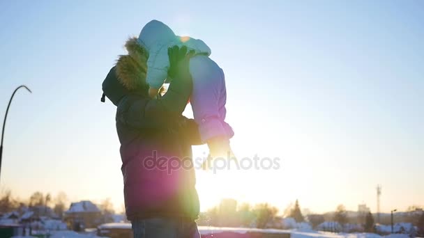 Guy παίζει με μωρό στο ηλιοβασίλεμα στη διάρκεια του χειμώνα. Ρίχνει επάνω πάνω από το κεφάλι σας — Αρχείο Βίντεο