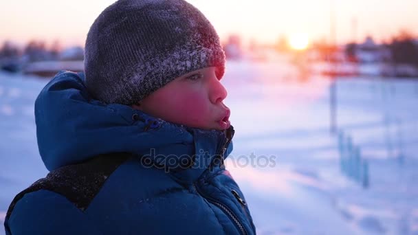 Ребенок делает пар изо рта в холодный солнечный день — стоковое видео