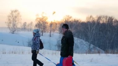 Aile snowtube.slow hareket ile karlı tepe yükselir. kar kış manzara. Günbatımı Zamanı