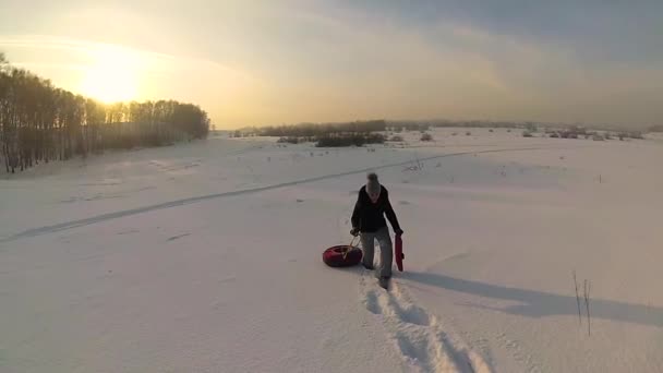 Das Mädchen steigt mit snowtube.slow motion auf einen verschneiten Hügel. Schneelandschaft. Sonnenuntergang — Stockvideo