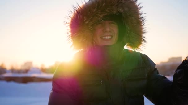 A srác, intett a kezével, és télen napnyugtakor vígan nevetett. havas téli táj. a szabadban — Stock videók
