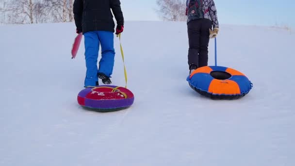 La familia se eleva a la colina nevada con snowtube.slow movimiento. nieve invierno paisaje. Tiempo de puesta del sol — Vídeos de Stock