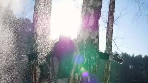 Ein Mädchen wirft hinter einem Baum Schneebälle. sonniger Tag — Stockvideo