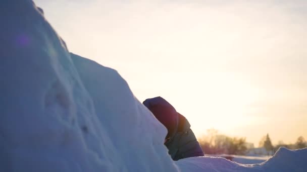 Gamin jouant dans les montagnes enneigées, pour grimper au sommet. Au coucher du soleil — Video