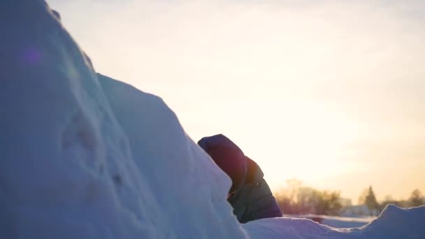 Criança brincando em montanhas nevadas, para subir ao topo. Ao pôr do sol — Vídeo de Stock