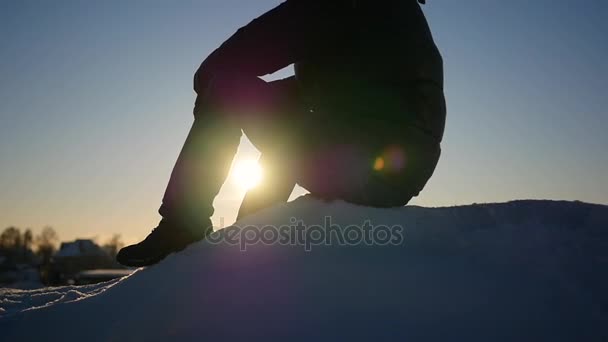 Парень, сидящий высоко на снежном склоне. снежный зимний пейзаж. спорт на открытом воздухе — стоковое видео