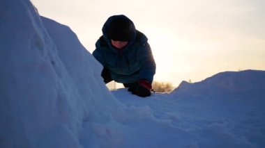 Zirveye tırmanmak için karlı dağlarda, oynayan çocuk. Gün batımında