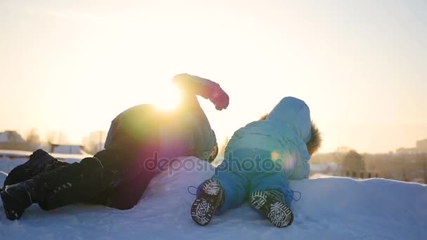 Crianças brincando em uma colina nevada. Paisagem de inverno. Hora do pôr do sol — Vídeo de Stock