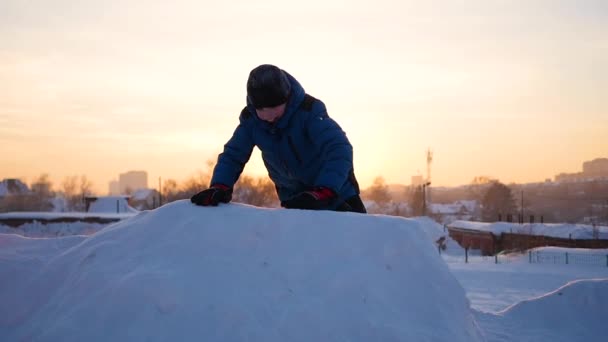 Niño jugando en las montañas nevadas, para subir a la cima. Al atardecer — Vídeos de Stock