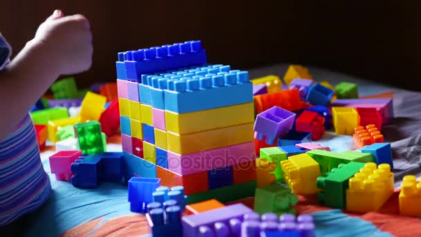 Un bambino gioca nel costruttore. Gioco del designer per bambini. Cubi colorati . — Video Stock