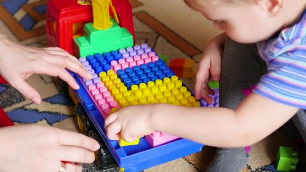 Uma criança pequena brinca no construtor. Jogo do desenhista de crianças. Cubos coloridos . — Vídeo de Stock