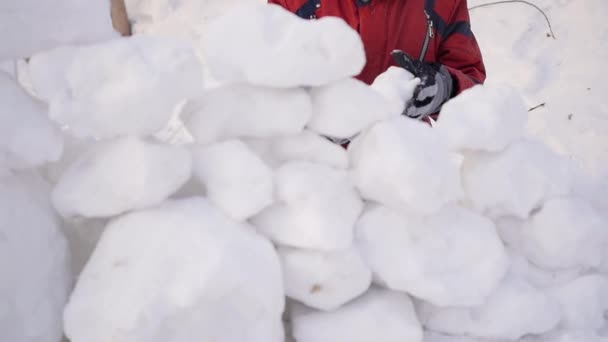 Gyermek játék a szabadban, télen. A gyermek épít egy falat, hó kövek — Stock videók