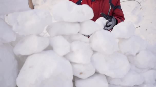 Kinder spielen im Winter im Freien. das Kind baut eine Mauer aus Schneesteinen — Stockvideo