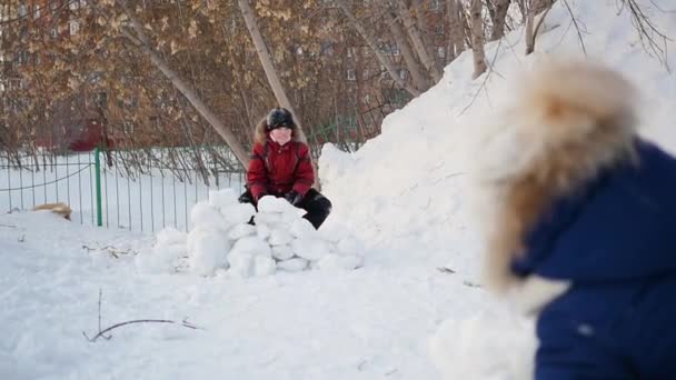 Boy and girl playing outdoors in winter. Children throw snowballs — Stock Video