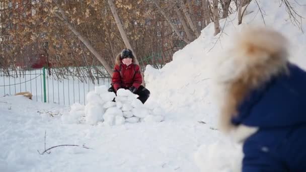 Garçon et fille jouant dehors en hiver. Les enfants jettent des boules de neige — Video