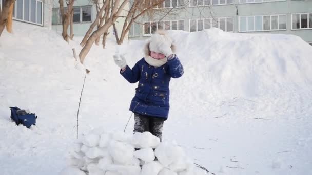 Chica jugando al aire libre en invierno. Los niños lanzan bolas de nieve — Vídeo de stock