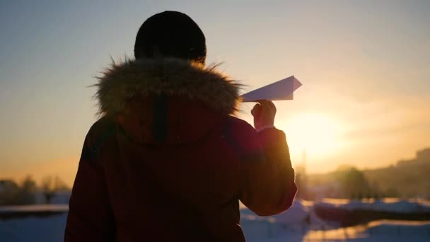 Dziecko na niebie uruchamia papierowy samolot o zachodzie słońca. Zimowy mroźny dzień — Wideo stockowe