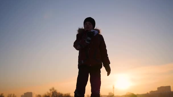 Kind am Himmel startet bei Sonnenuntergang ein Papierflugzeug. Frostiger Wintertag — Stockvideo