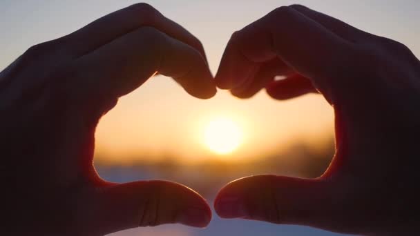 Meisje maken van hart met handen in de zon. Silhouet hand in hart vorm met binnen de zonsondergang. Winter — Stockvideo