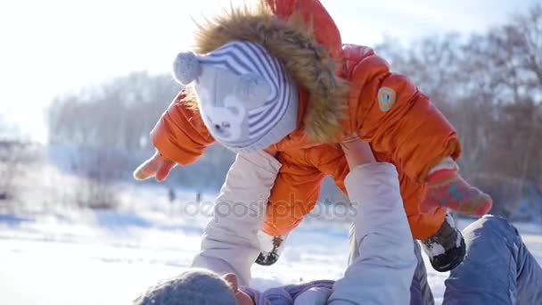 A menina brinca com o bebê no sol no inverno. Segurando as mãos — Vídeo de Stock