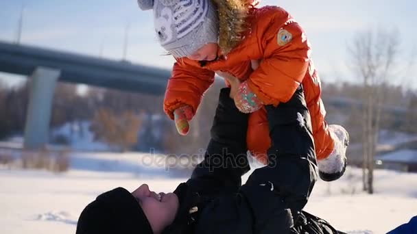 晴れた冬の時間であなたの子供と遊ぶ男。彼の腕の中で保持しています。冬の風景 — ストック動画