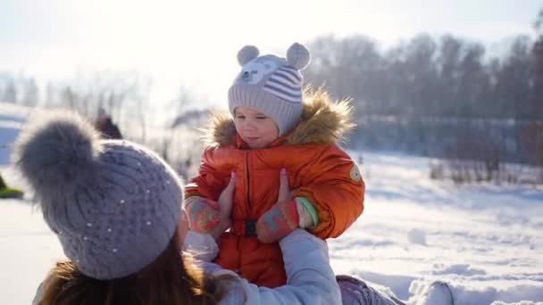 Flicka leker med barnet på soliga vintertid. Håller på händer — Stockvideo