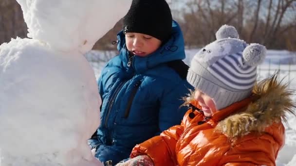 Barn att göra en snögubbe på lekplatsen — Stockvideo