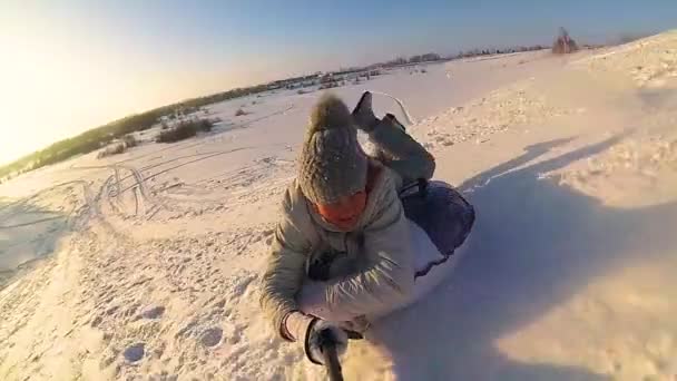 Joyeuse fille chevauche et souriant snowtube sur les routes enneigées. au ralenti. neige hiver paysage. sports de plein air — Video