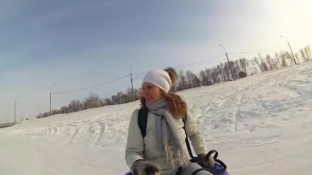 Joyeuse fille chevauche et souriant snowtube sur les routes enneigées. au ralenti. neige hiver paysage. sports de plein air — Video