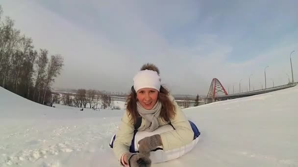 Menina feliz passeios e sorrindo tubo de neve em estradas nevadas. câmara lenta. neve paisagem de inverno. esportes ao ar livre — Vídeo de Stock