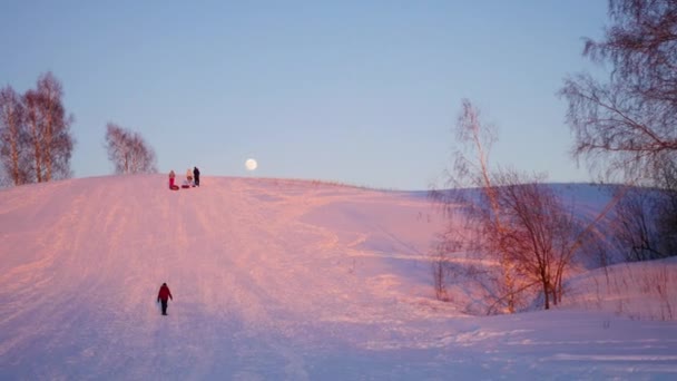 Paisaje de invierno. Hora del atardecer. la gente sube la colina nevada — Vídeos de Stock