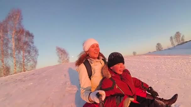 Ευτυχισμένη οικογένεια βόλτες και χαμογελαστά snowtube στη χιονισμένη roads.slow κίνηση. χιόνι χειμερινό τοπίο. Υπαίθρια σπορ. Ηλιοβασίλεμα — Αρχείο Βίντεο