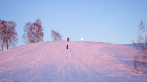 Paisagem de inverno. Hora do pôr-do-sol. as pessoas escalam a colina nevada — Vídeo de Stock