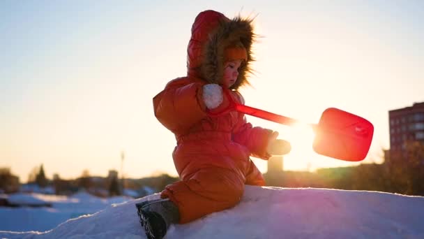 Criança brincando em uma colina nevada. Paisagem de inverno. Hora do pôr do sol — Vídeo de Stock