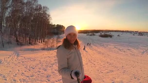 Das Mädchen steigt mit dem Schneeröhrchen auf einen verschneiten Hügel. Zeitlupe. Schneelandschaft. Aktive Erholung, Sport — Stockvideo