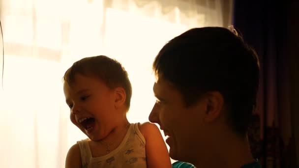 Vater hält Sohn zu Hause durch die Sonne. Spaß beim spielerisch lachenden Papa in Zeitlupe — Stockvideo