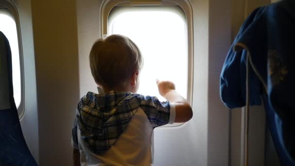 Küçük çocuk uçak pencereden dışarı bakarak — Stok video