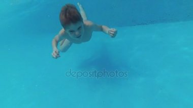 havuzda suyun altında keyfi ile mutlu bir çocuk yüzüyor