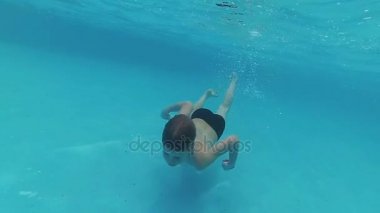 havuzda suyun altında keyfi ile mutlu bir çocuk yüzüyor