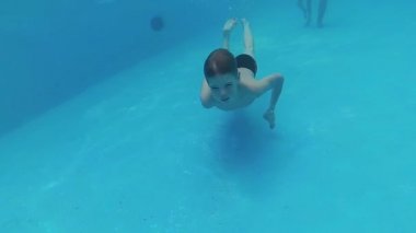 havuzda suyun altında keyfi ile mutlu bir çocuk yüzüyor