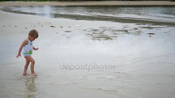 Dziecko radośnie biegnie wzdłuż plaży, tworzenie aerozolu wody — Wideo stockowe