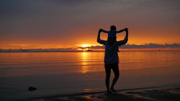 Das Mädchen mit dem Kind spazieren gehen und bei Sonnenuntergang am Strand spielen — Stockvideo