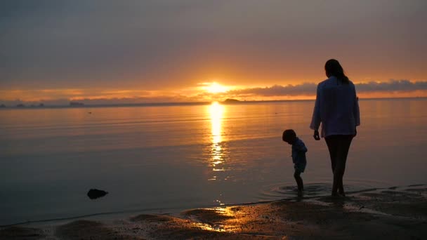 La chica con el niño ir a pasear y jugar en la playa al atardecer — Vídeos de Stock