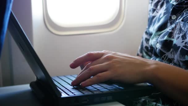 Tipo trabajando en el portátil en el avión cerca de la ventana — Vídeos de Stock